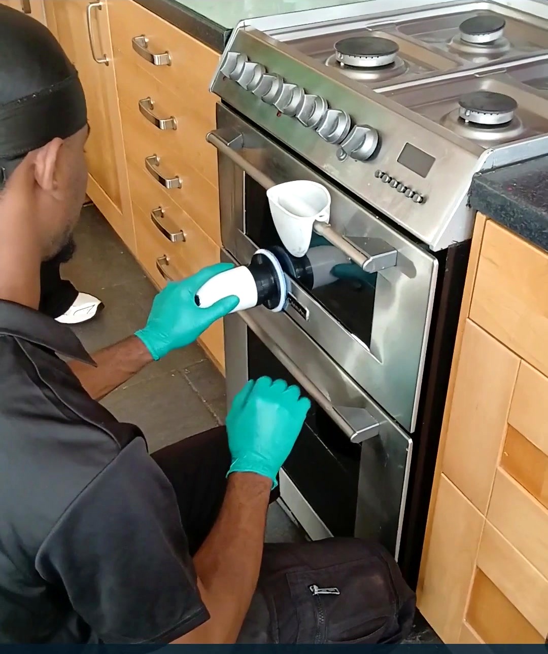 Good Hands cleaner using a steam cleaning tool to clean an oven door and glass